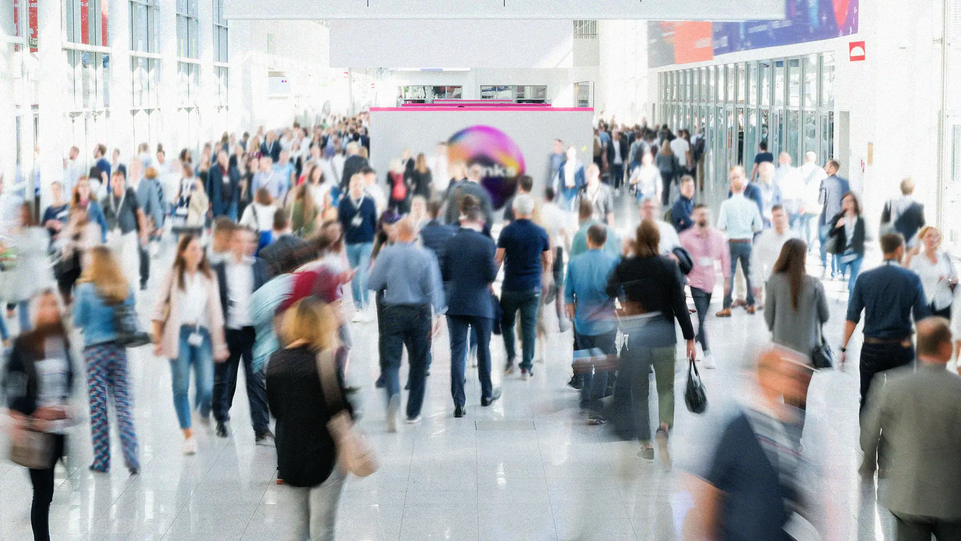 A convention center during an industry event with many people walking through. There is a booth for Monks. It is a well lit hall with lots of windows.