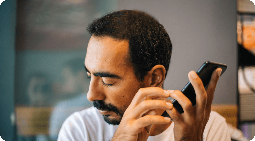 A man holds up a mobile phone to his ear to hear instructions from his screen reading technology.