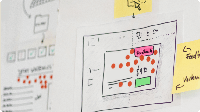Image of a sketch with sticky dot votes on it and a sticky note next to it saying "Feedback".