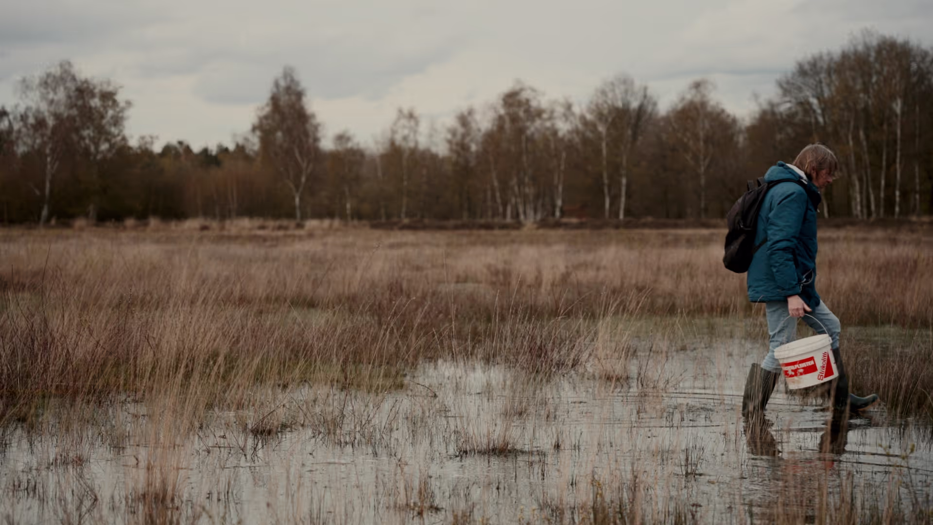 Woman walks through a pond looking for amphibians and small critters.