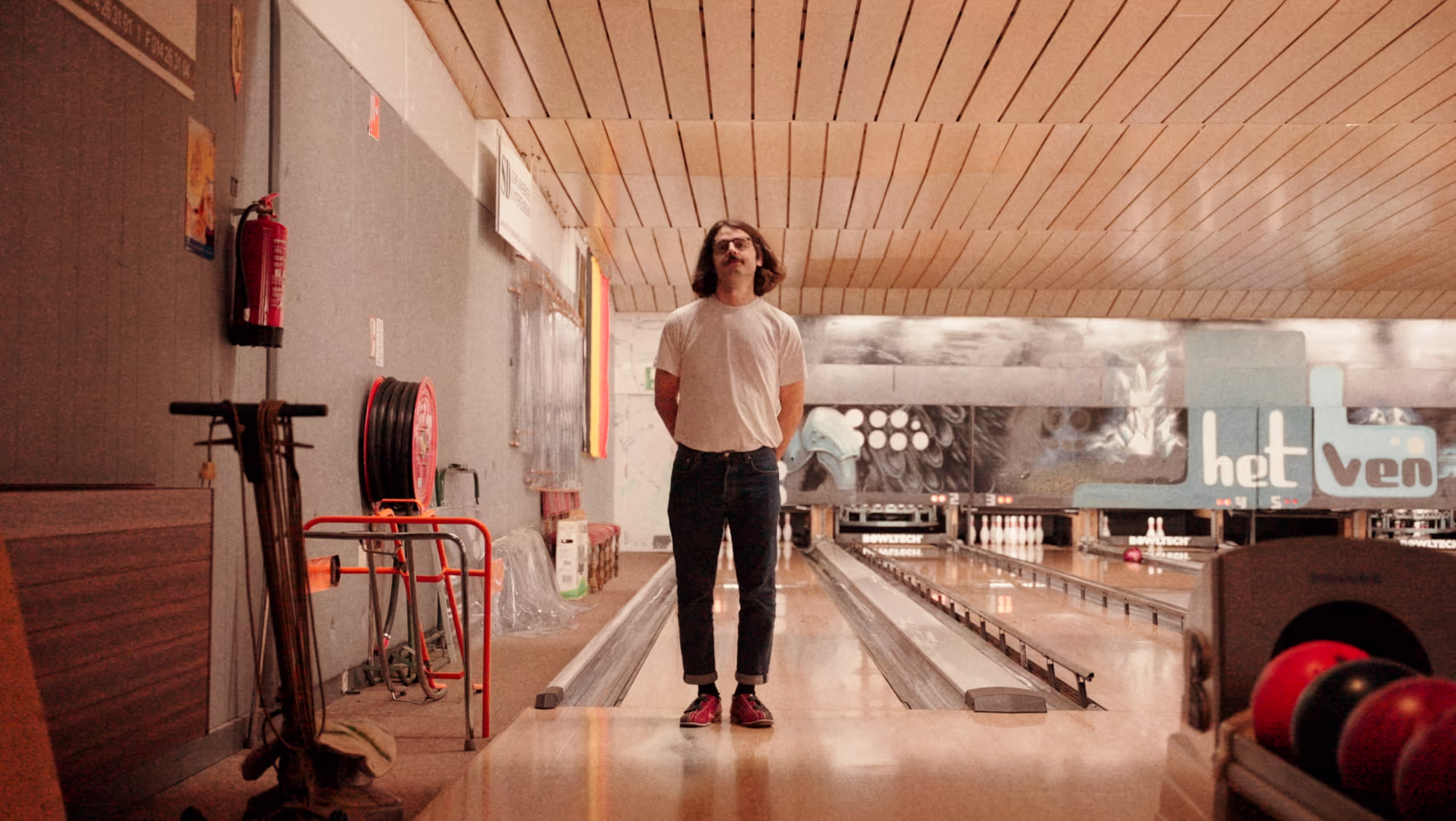 Man singing in front of a bowling lane.