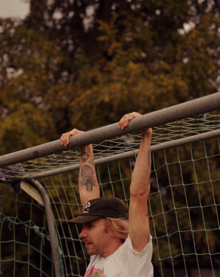 Man hanging from the frame of a goal.