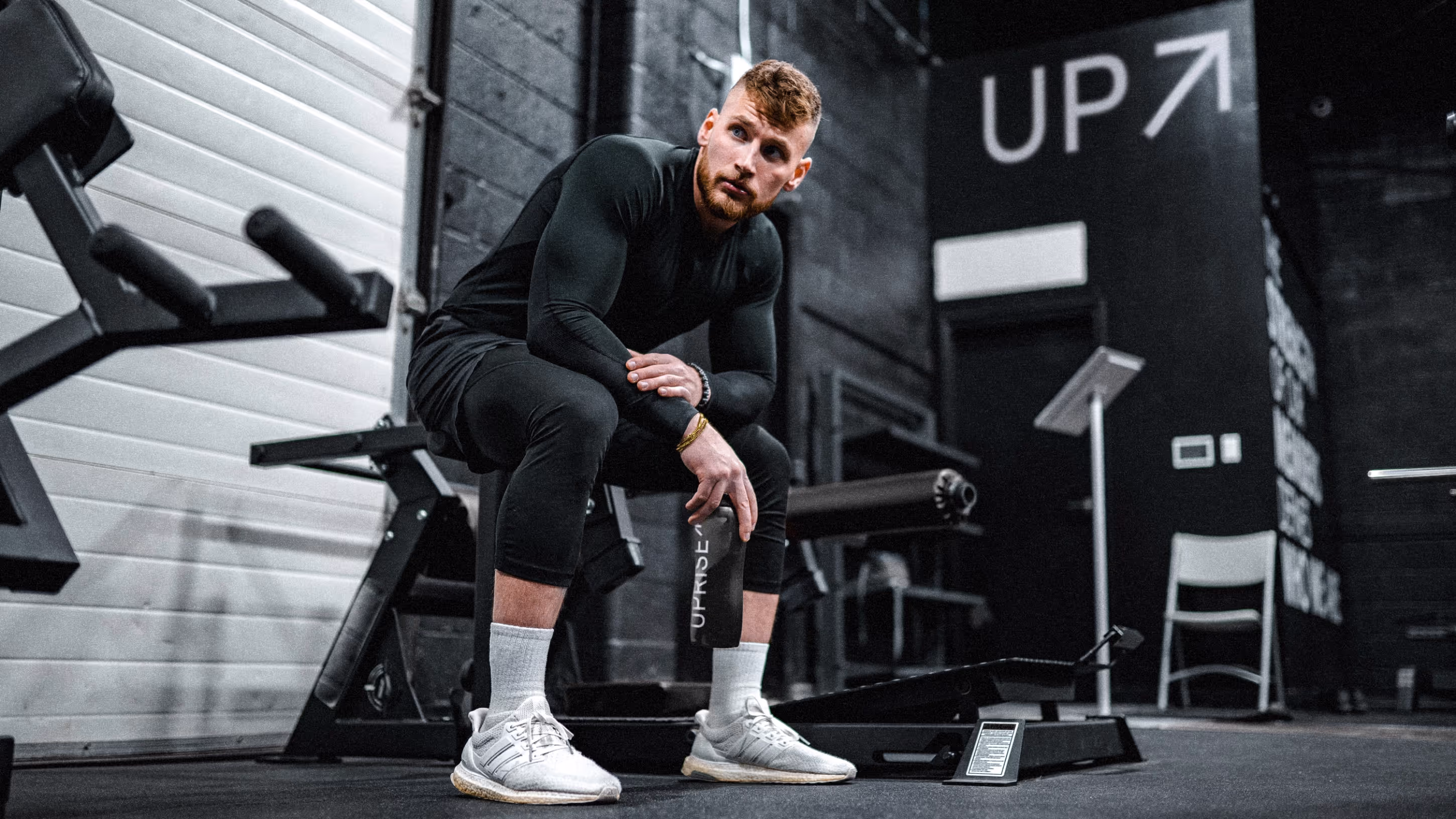 Een man die op een bank in de fitness van Uprise zit.