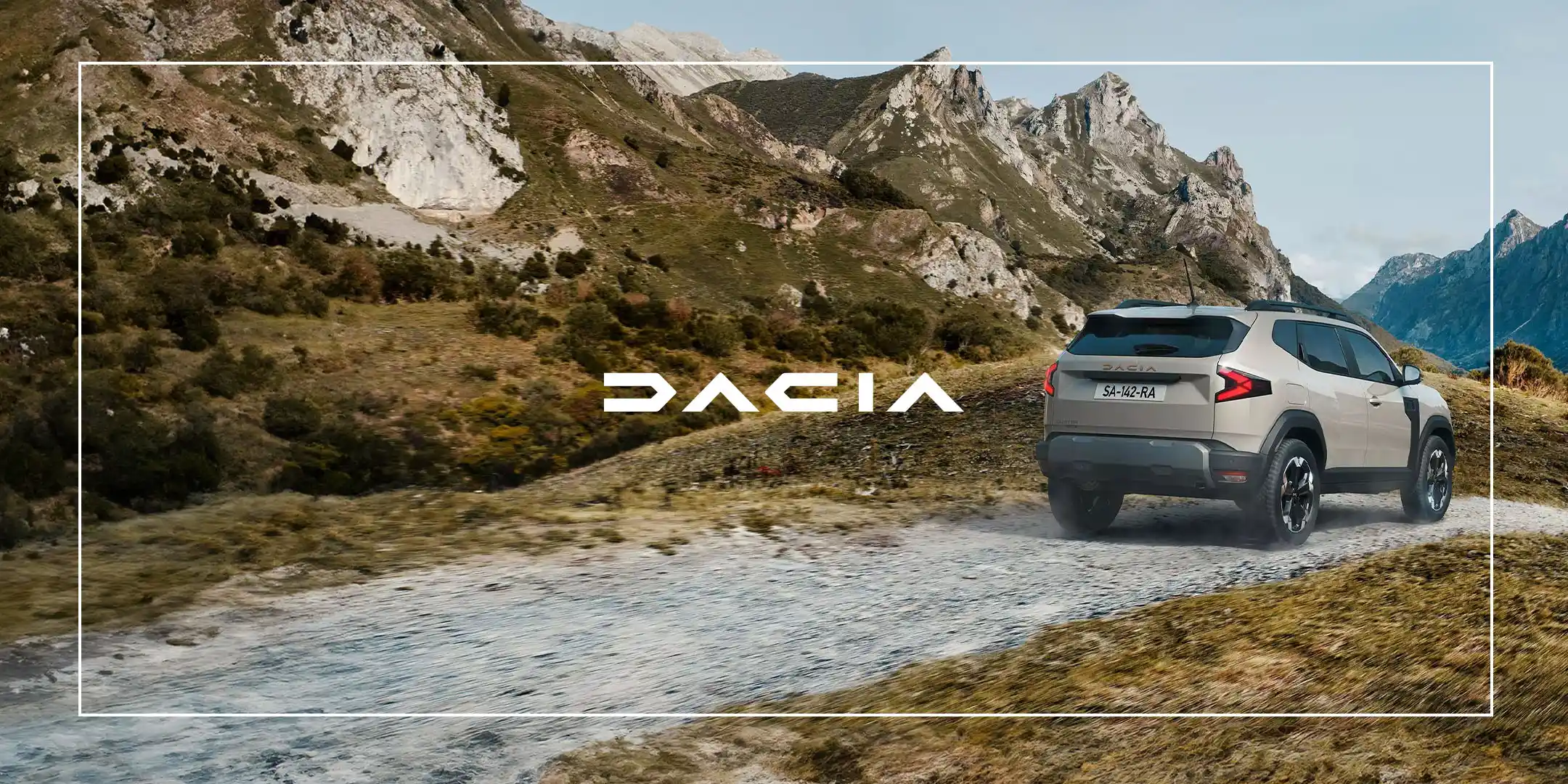 Dacia SUV kjører på en grusvei i fjellandskap med fjell i bakgrunnen.