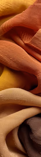 Close-up of layered, folded fabric in shades of orange, yellow, beige, and brown.