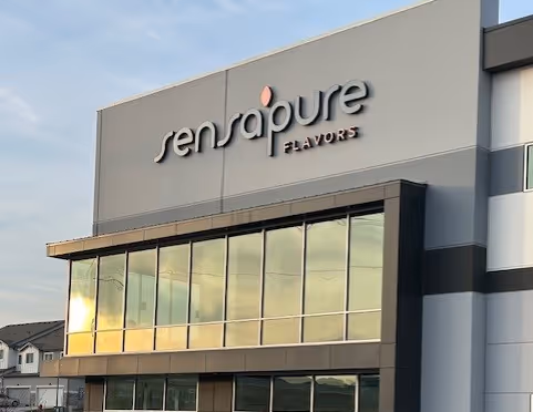 Modern building exterior with large windows and the sign 'sensapure FLAVORS' on the upper facade.