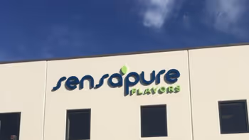 Facade of a building with the logo 'sensapure FLAVORS' under a blue sky with a small cloud.