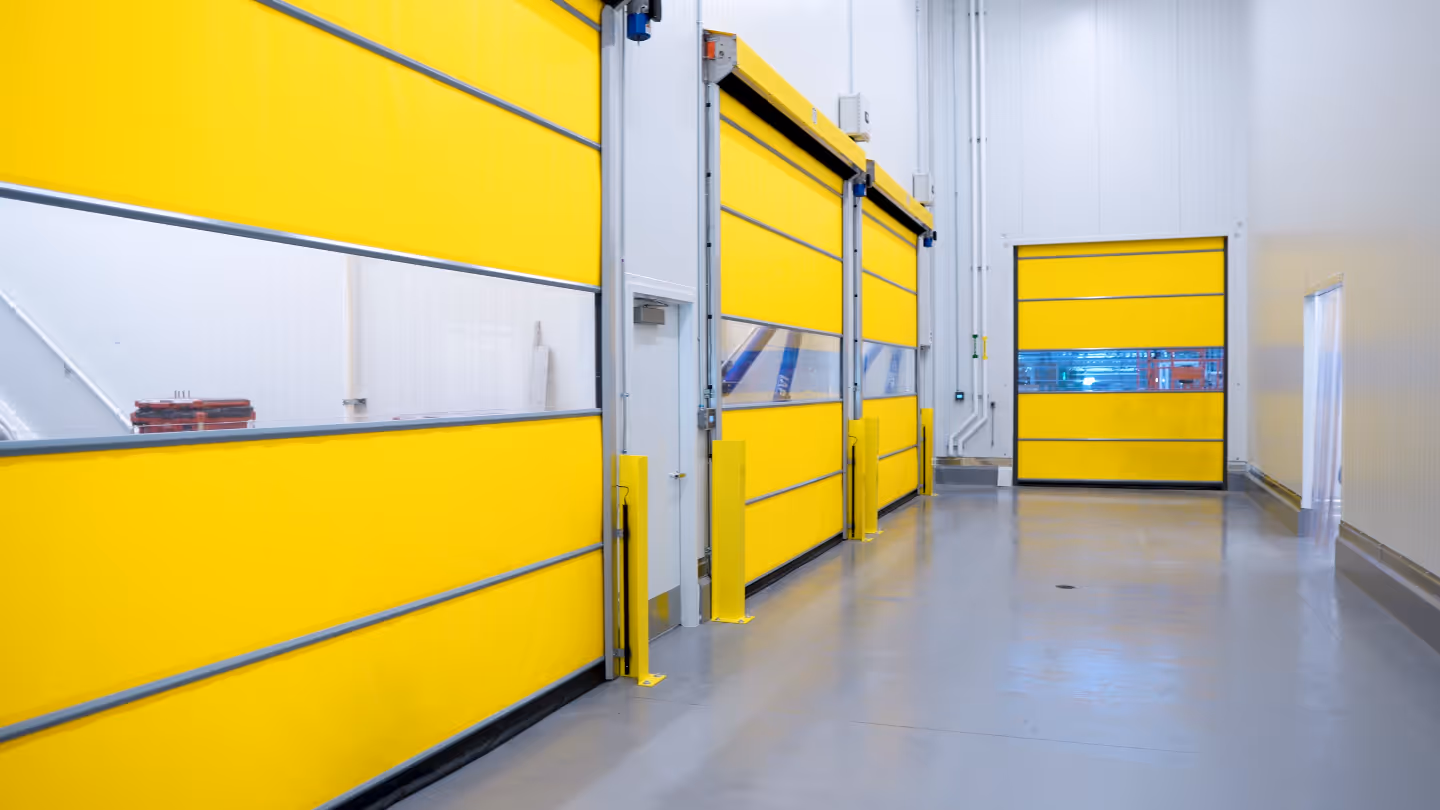 Industrial interior with bright yellow high-speed roll-up doors with transparent middle panels.