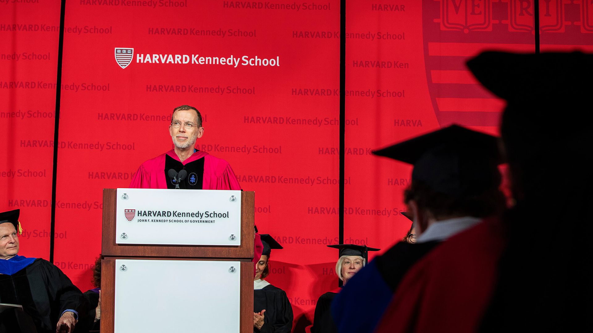 Dean Doug Elmendorf speaking at HKS Commencement with logo prominently displayed for video and photography documentation of the event