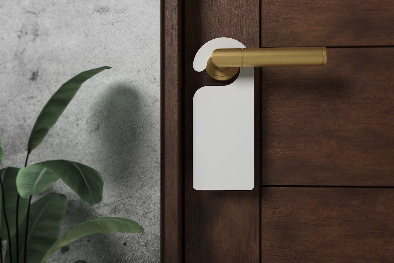 Blank white door hanger mockup hanging on a silver door handle.