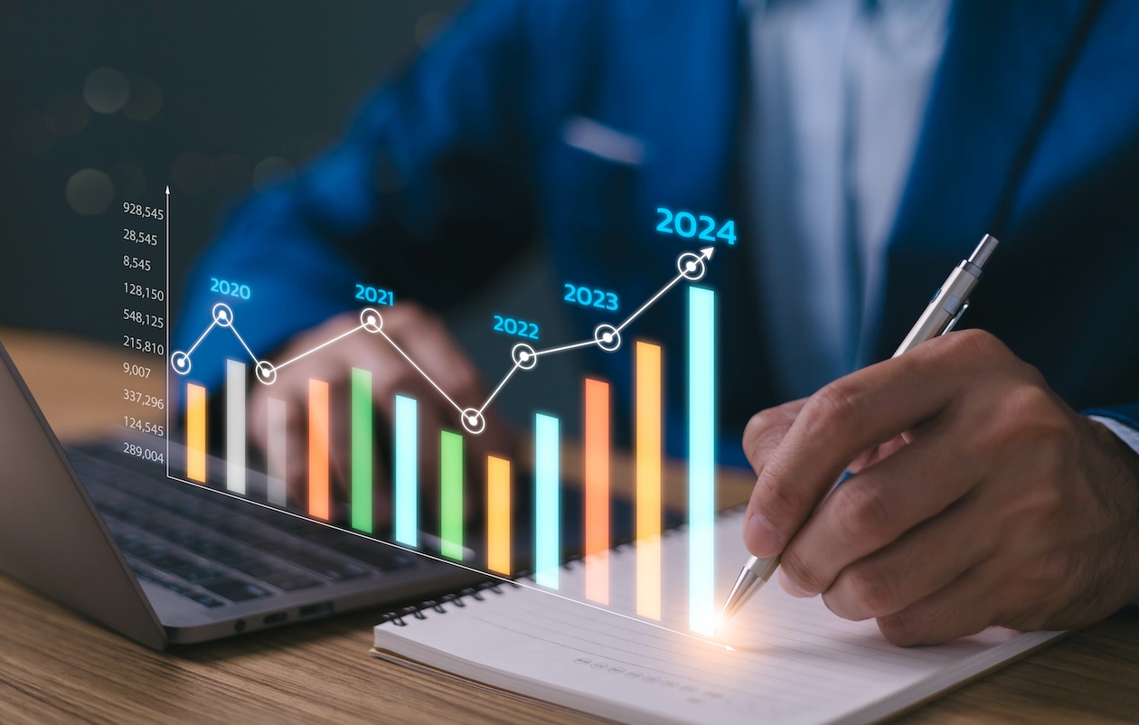 Businessman reviewing a financial growth chart with upward revenue trends from 2023 to 2024.