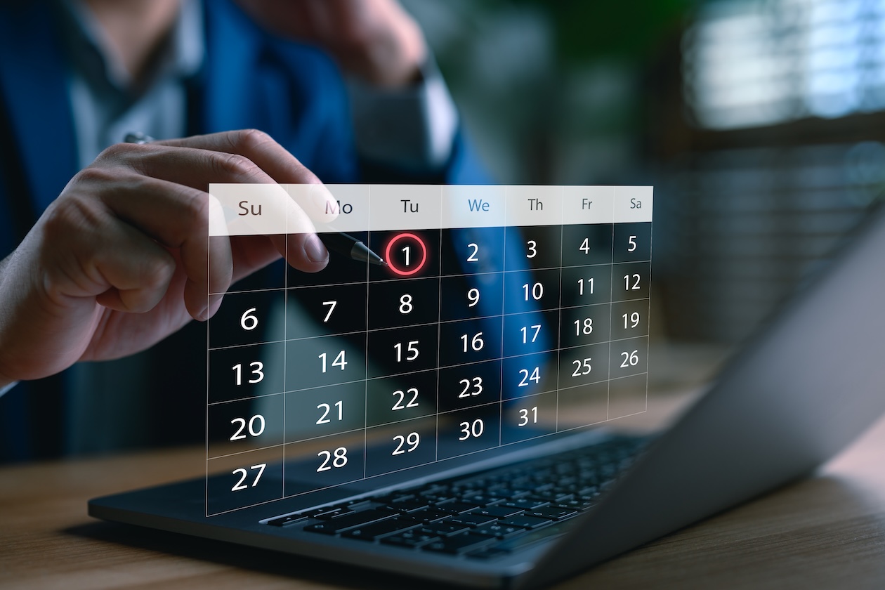Business professional managing a digital calendar on a laptop, highlighting the first of the month to represent scheduling, appointment booking, and time management.