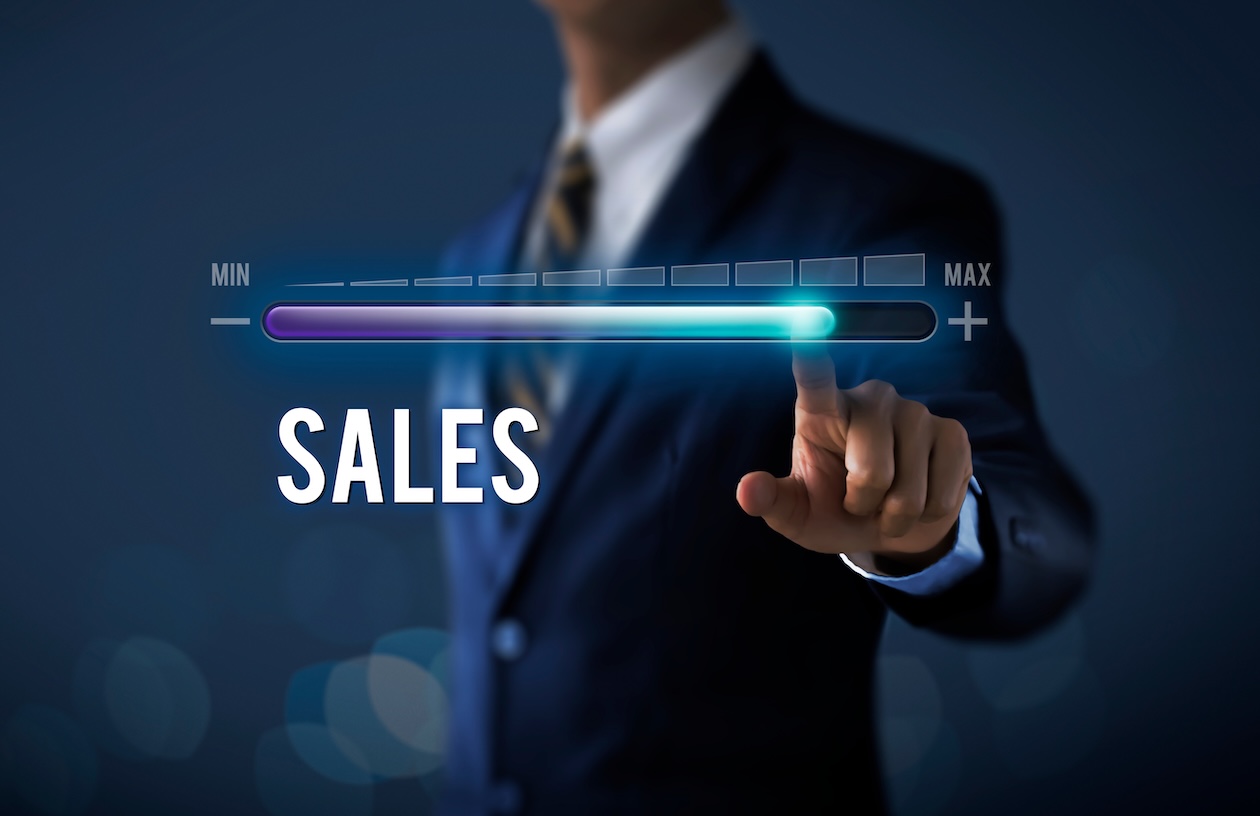 Businessman pulling upward a progress bar labeled “Sales,” symbolizing revenue growth and increased business performance.