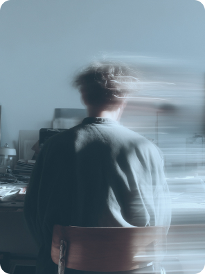 Artistic photo of a blurred person sitting at a desk, symbolizing motion and focus.