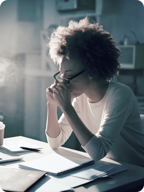 Focused woman working at a desk with documents and coffee in soft morning light.