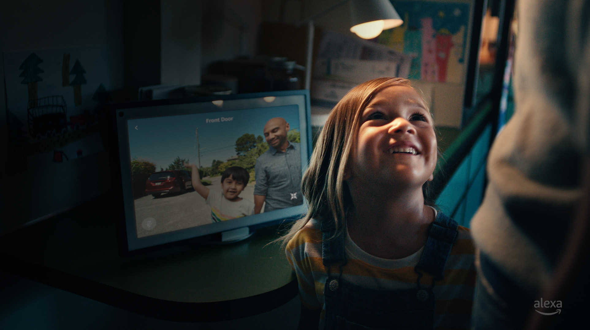 A girl smiles as two visitors are shown in the Amazon Alexa door camera display