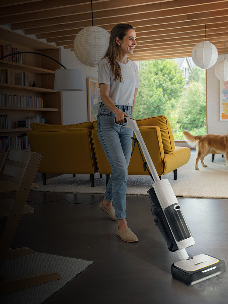 A woman cleans her floor with a Kärcher SCV4