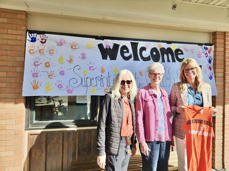Meadows Valley Schools Superintendent Dee Fredrickson, Meadows Valley School Board member Barbara Dixon and State Superintendent of Education Debbie Critchfield stand in front of a handmade sign welcoming Critchfield to the school.