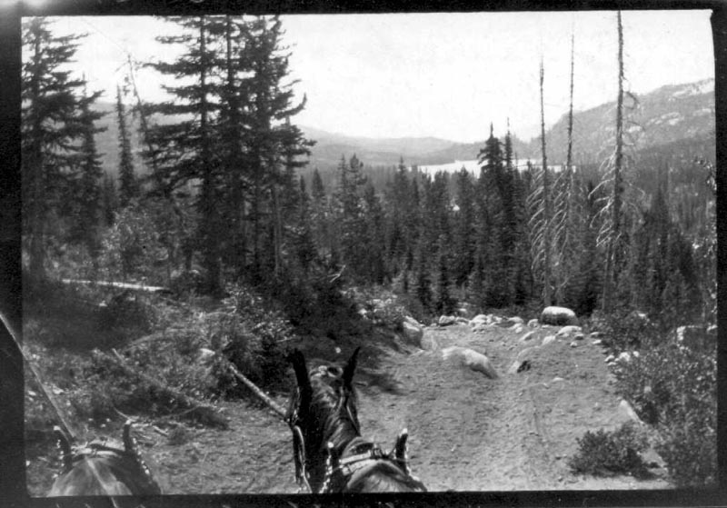 This is a road north of McCall about 1902, with Little Payette Lake visible in the distance. (The lake was enlarged in 1926 when a small dam was added.) This is probably a typical example of early roads to mining camps. Notice the rocks.