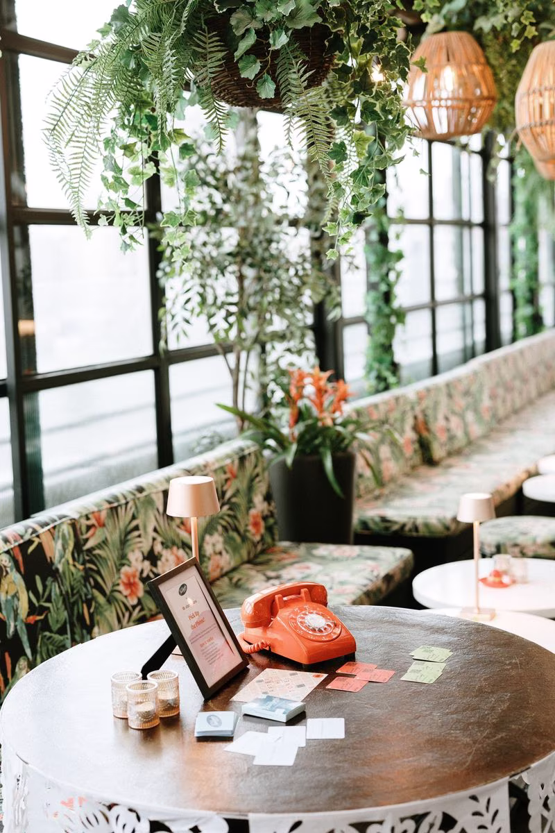 orange phone audio guest book sitting on table with plants around the room