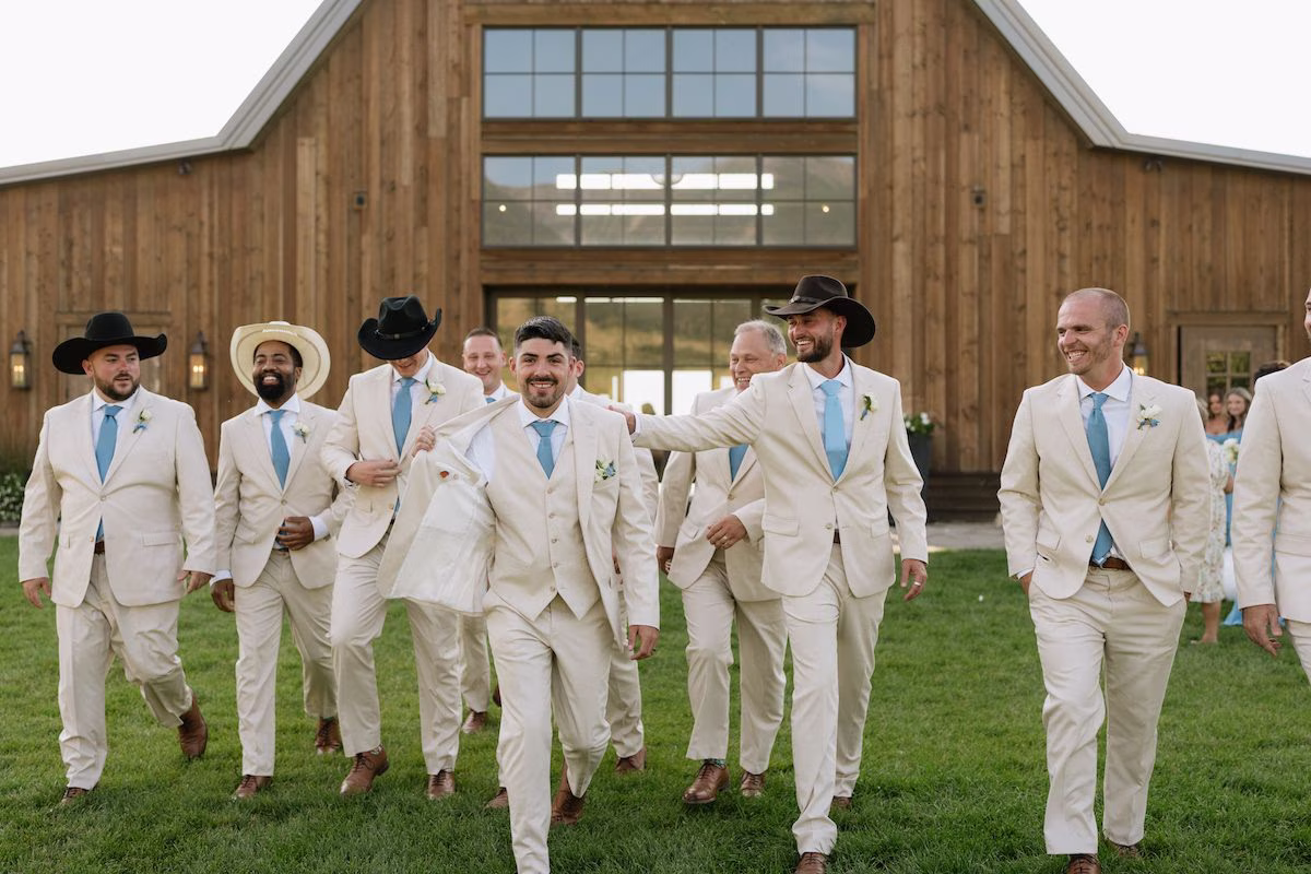 Groomsmen in beige color suits walking toward camera at outdoor wedding