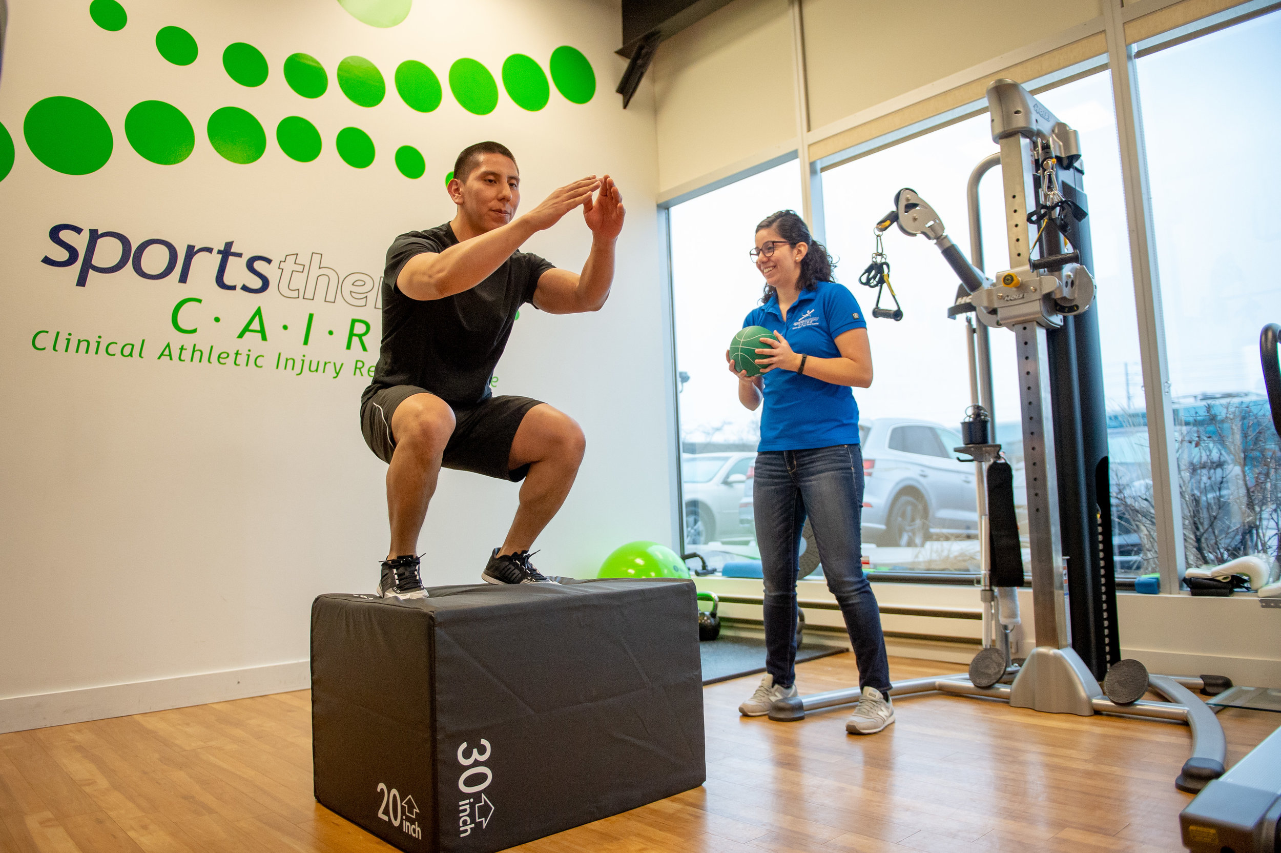 Athletic therapist coaching a patient through a box jump