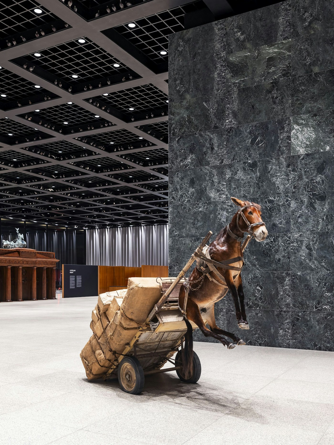 Maurizio Cattelan burdened donkey installation in NIGHT at Neue Nationalgalerie