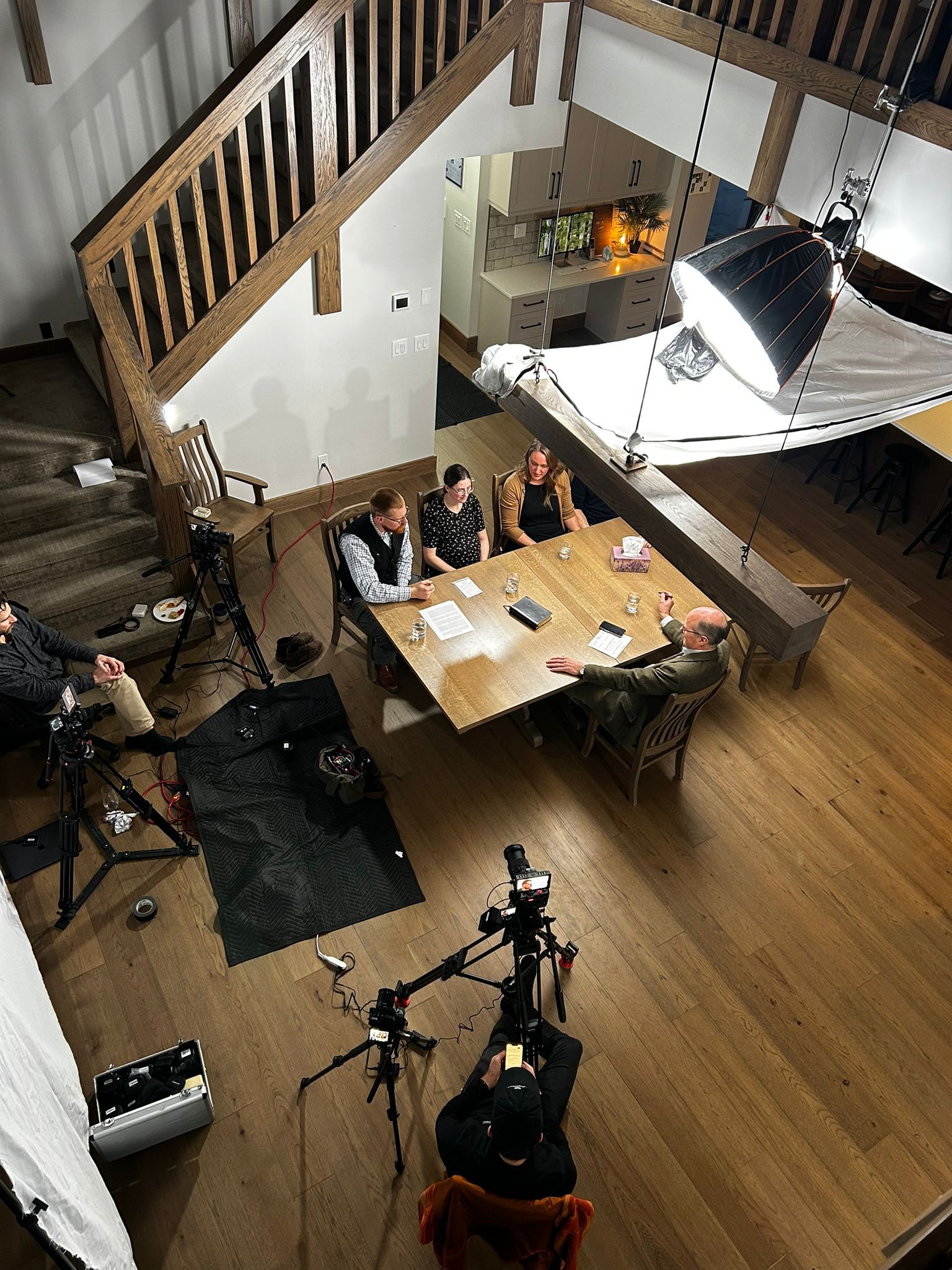 Overhead view of a three-camera podcast setup around a dining table in a two-story Winnipeg house.