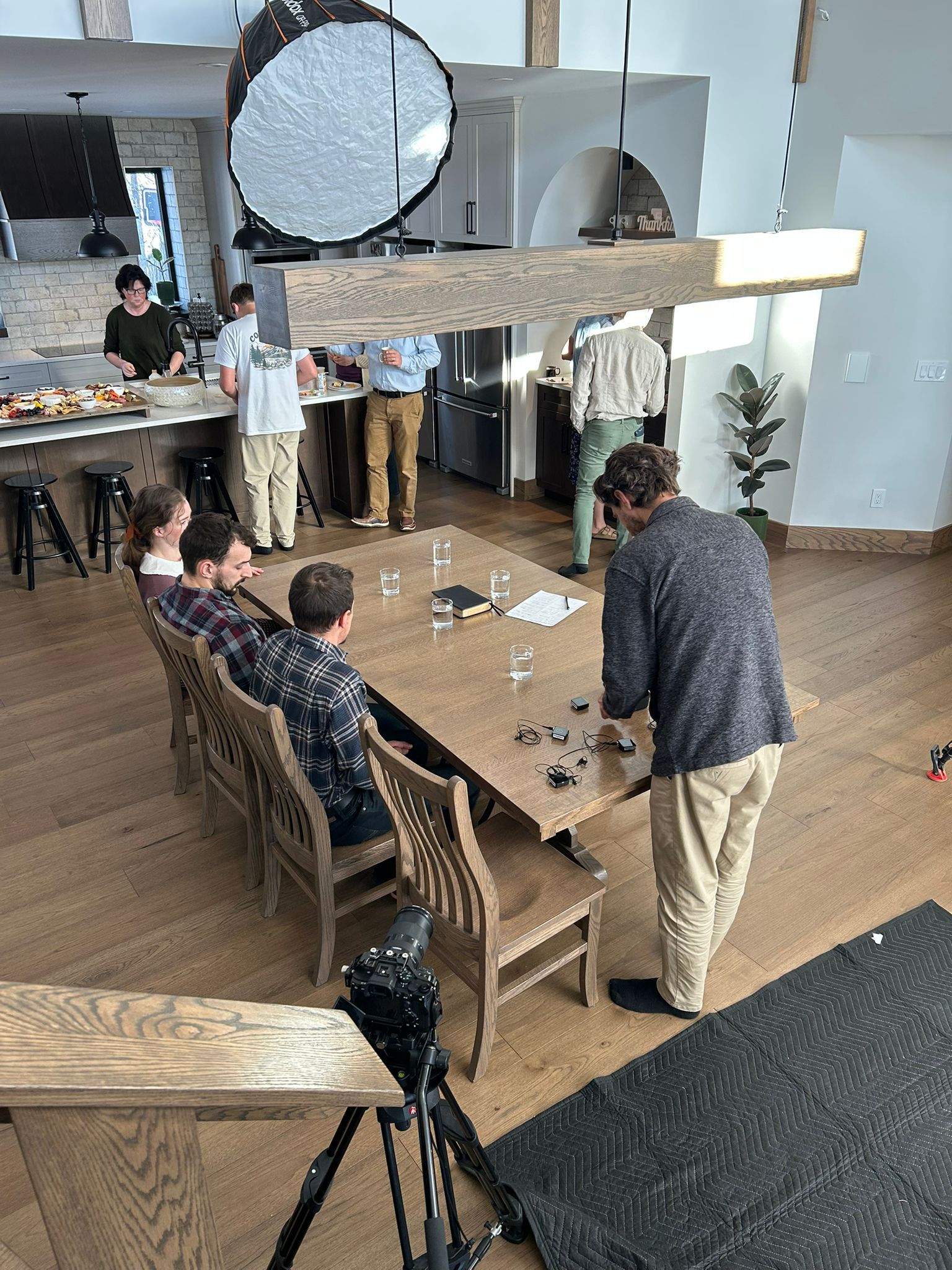 Behind the scenes of the Winnipeg podcast shoot, with the crew preparing lavalier microphones around a dining table.