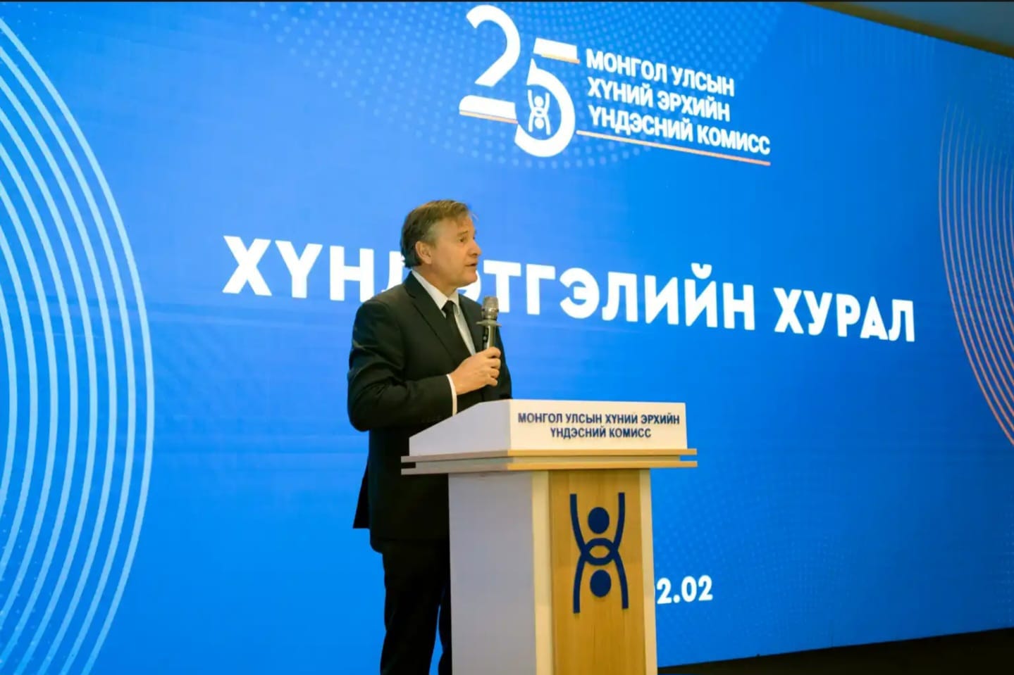Conference speaker at a blue backdrop in Ulaanbaatar