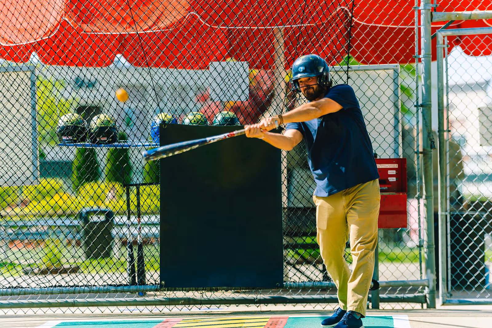 A man is playing inside the batting cage
