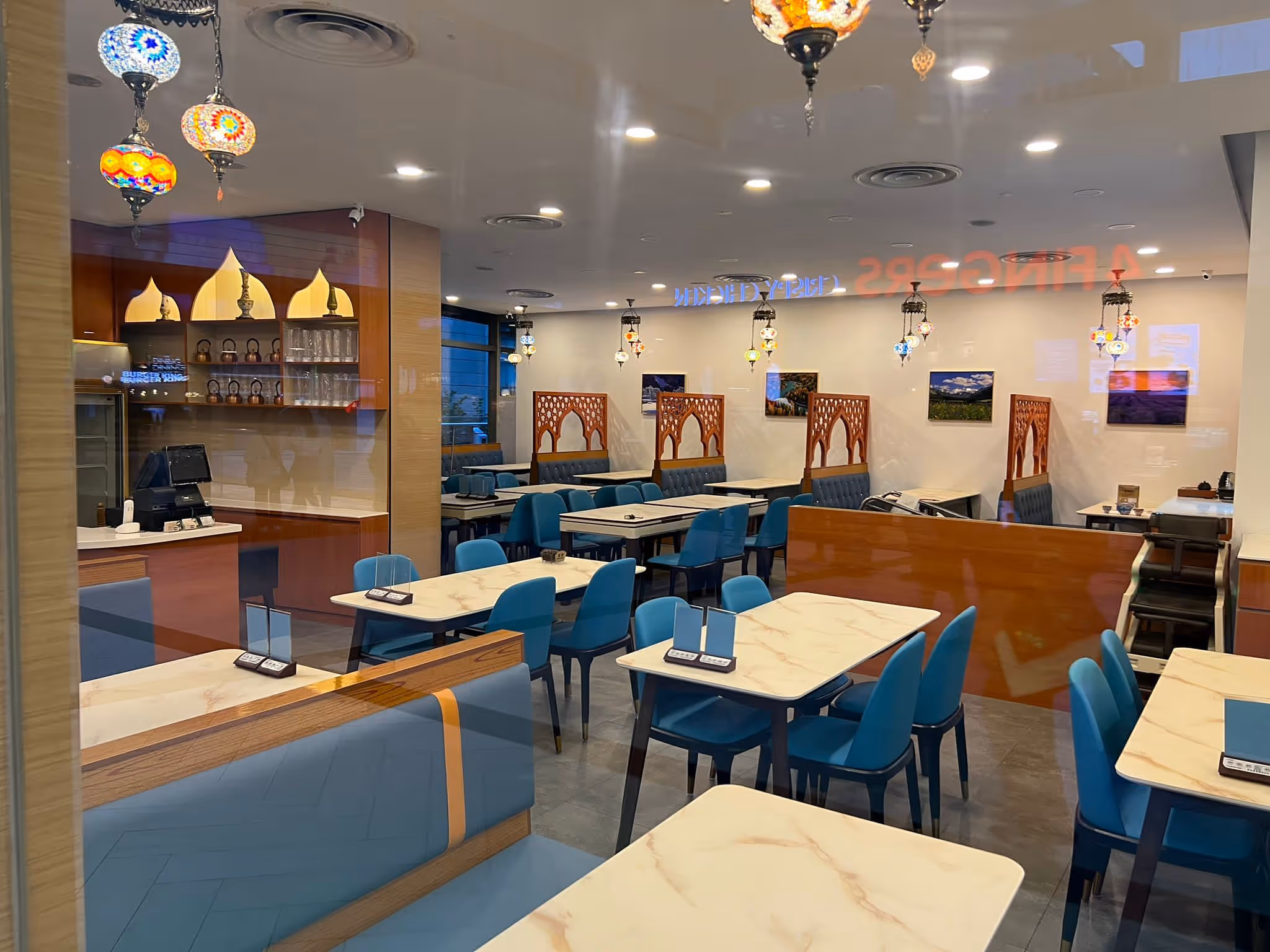 Interior photographs of Marina Square Branch. There are marble tables, blue chairs, wooden partitions, and colourful hanging lamps.