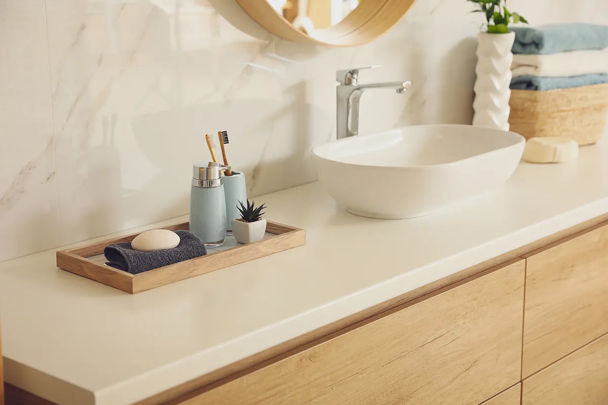 White vessel sink on a bathroom counter with toothbrushes and folded towels.
