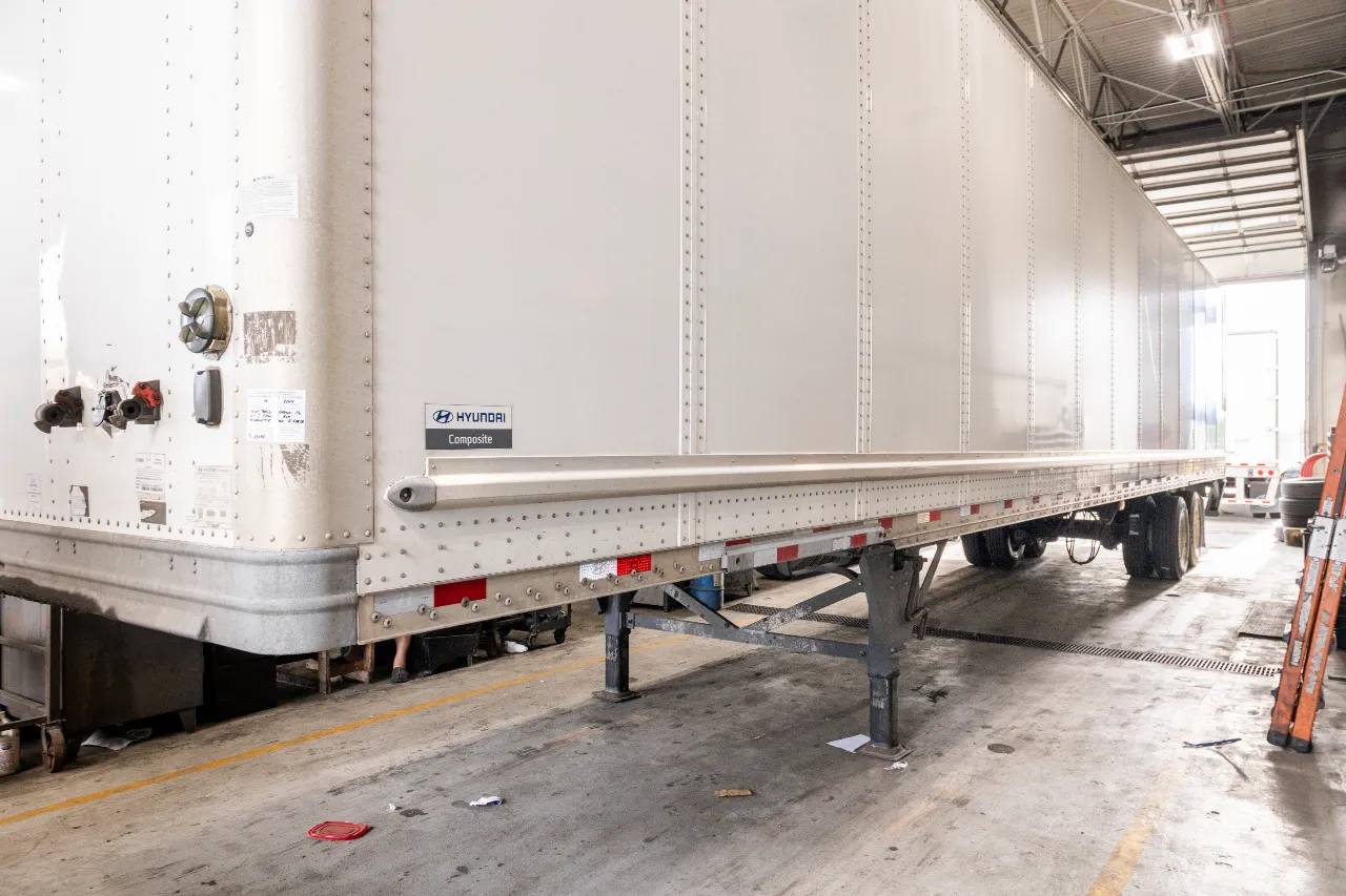 Trailer repair in progress with Hyundai Composite trailer parked on landing gear inside a service bay.