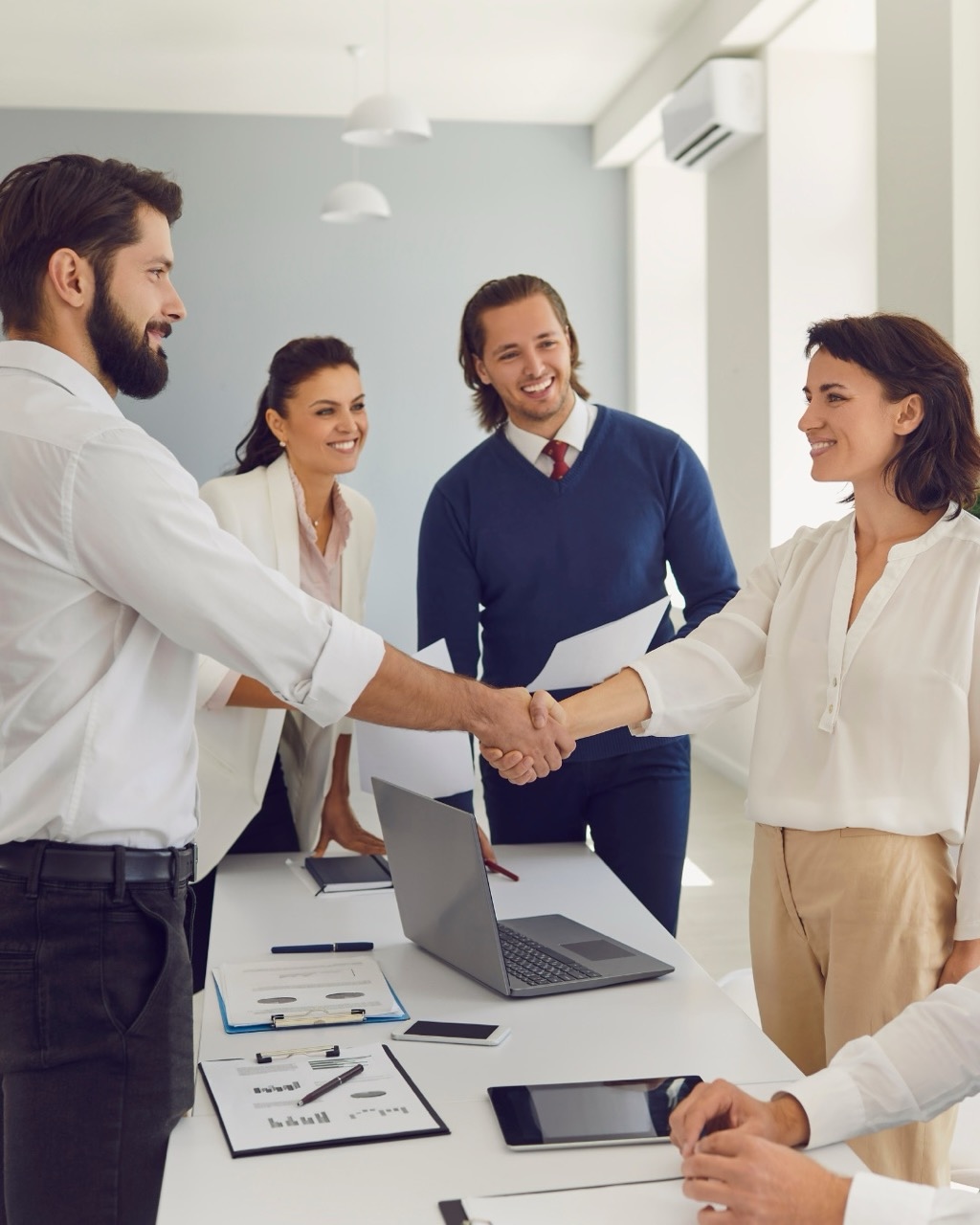 Professionnels chez Nitidis se serrant la main après une session de media training, entourés de collègues souriants.