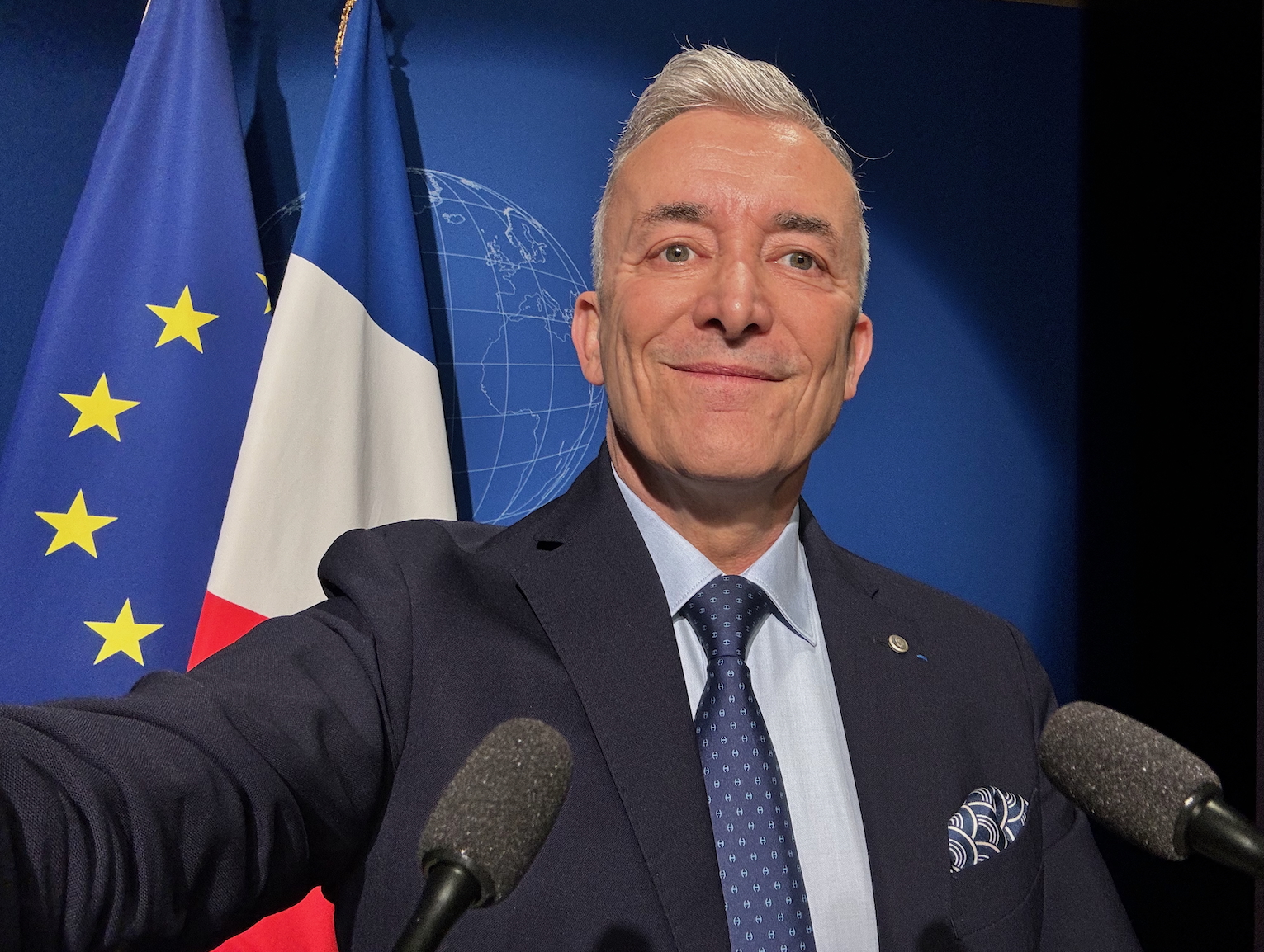 Laurent Vibert fondateur et dirigeant de l'agence Nitidis pose devant les drapeaux de la république au Ministère des Armées à Paris