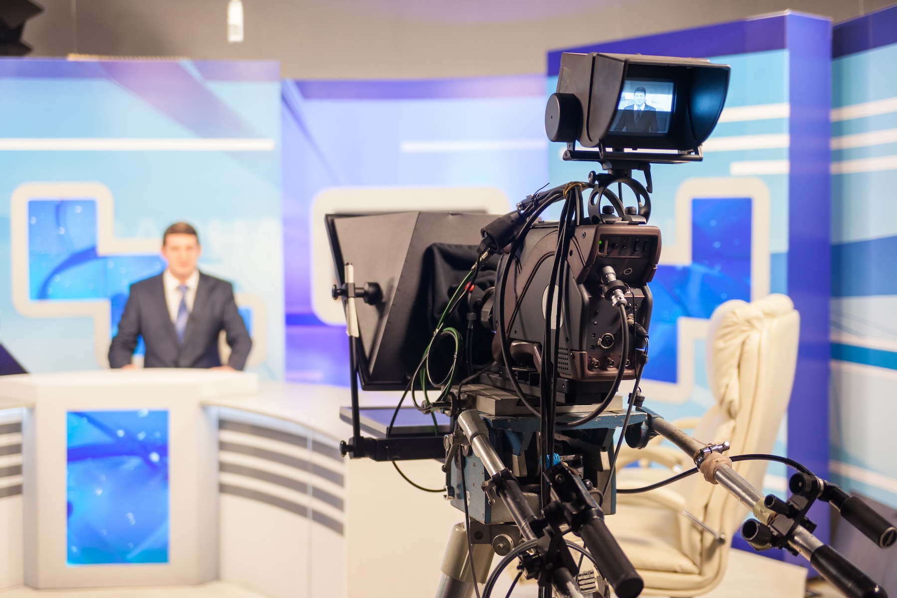 Un journaliste face à une caméra dans un studio d'une chaine d'info en continu