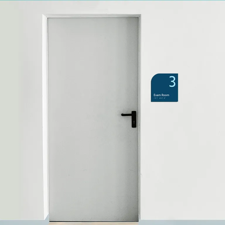 Closed gray door with a sign on the wall reading '3 Exam Room' next to it.