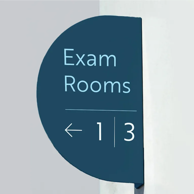 Wall-mounted sign reading 'Exam Rooms' with arrow pointing left toward rooms 1 and 3.