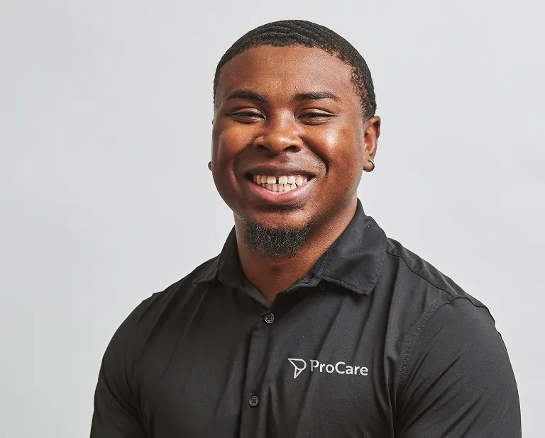 Smiling man wearing a black ProCare polo shirt against a plain light background.
