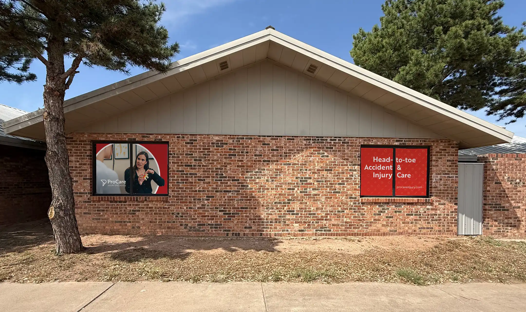Front view of a brick building with two windows displaying ProCare Injury Specialists branding and a sign reading 'Head-to-toe Accident & Injury Care'.