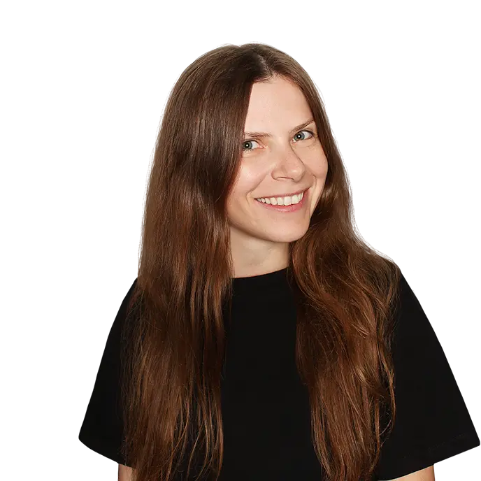 A person with long, brown hair wearing a black t-shirt stands against a plain black background.