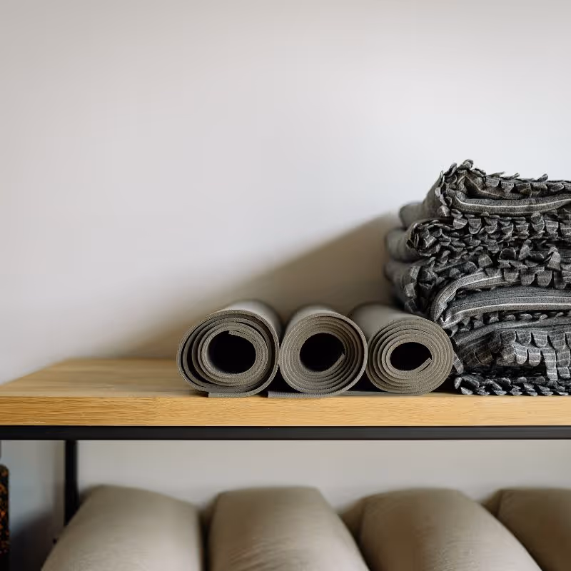 calming meditation space with soft natural light, featuring a sage green yoga mat, cozy linen blanket, warm wood accents, houseplants, and a candle-lit corner 
