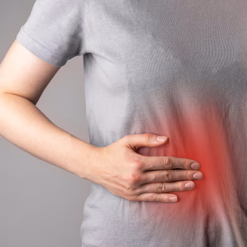 Person holding their side in discomfort with visible redness indicating inflammation in the abdominal area