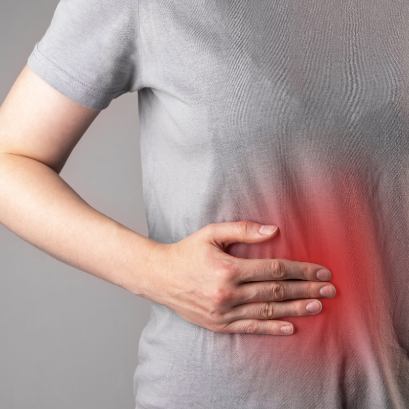 Person holding their side in discomfort with visible redness indicating inflammation in the abdominal area