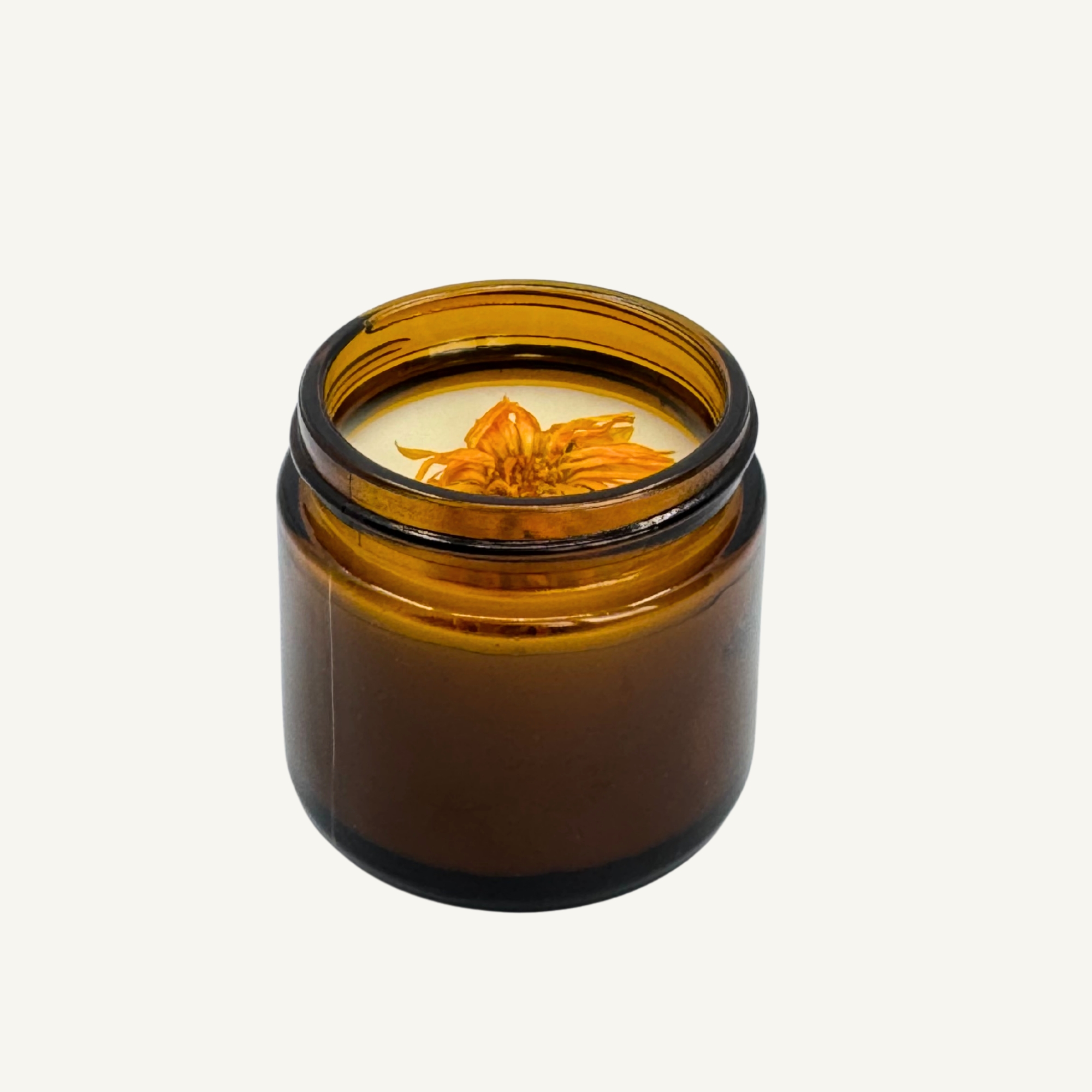 Top-down view of All Tree Roots 2 oz Calendula Salve in an amber glass jar, featuring organic calendula petals infused in a creamy herbal balm on a neutral background.