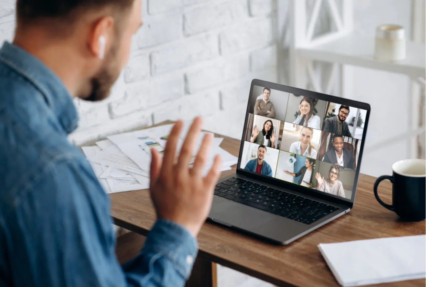 A man waves to his coworkers on a video call
