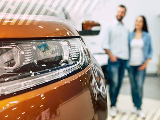 Happy couple viewing a used car at a dealership