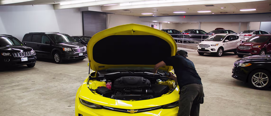 Mechanic looking under the hood of a car while reconditioning