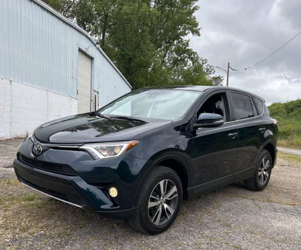 A black 2018 Toyota RAV4 parked next to a warehouse.